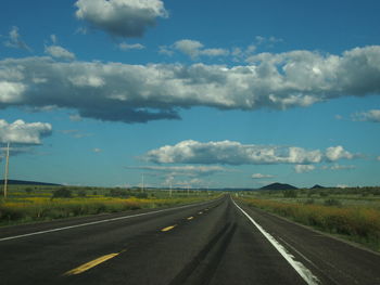 Road passing through landscape against cloudy sky