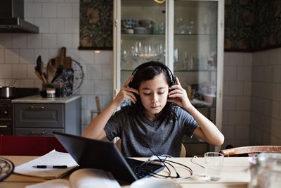 Young woman using phone while sitting on table