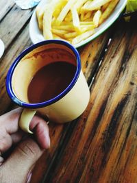 Cropped hand of person holding coffee cup on table