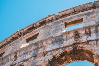 Low angle view of old ruin building against blue sky