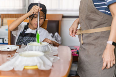 Mother with young son baking cake in kitchen