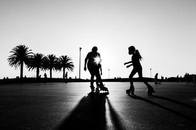 Silhouette people on street against clear sky