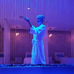 Woman playing with falling water decoration in illuminated room