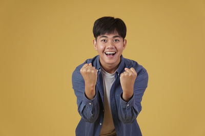 Portrait of smiling man standing against yellow background