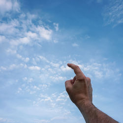 Cropped hand of woman gesturing against sky
