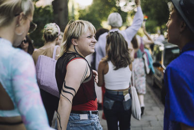 Happy non-binary person walking male and female friends