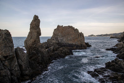 Rocks on sea shore against sky