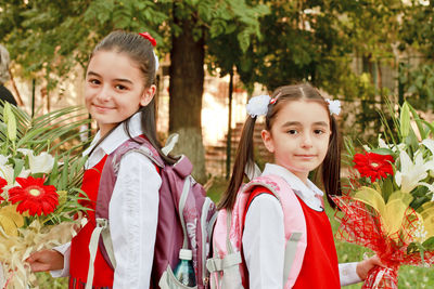 Portrait of smiling girls standing amidst flowering plants