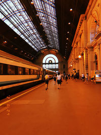 People walking on illuminated railroad station platform at night