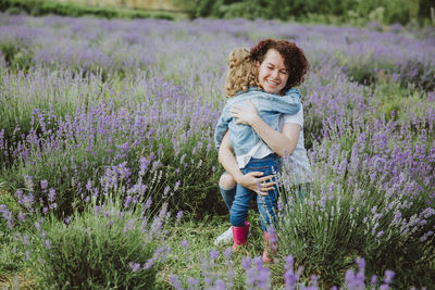 Full length of woman with purple flowers on field