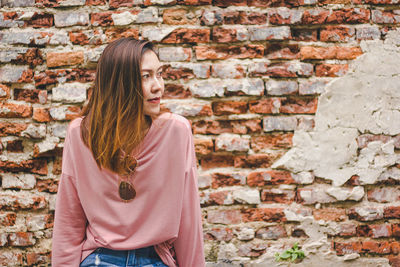 Midsection of woman standing against brick wall