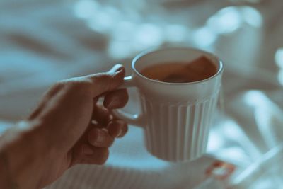 Close-up of human hand holding coffee cup at home