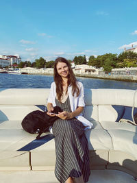 Portrait of young woman standing against lake