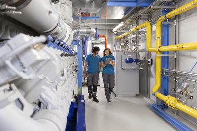 Technician colleagues discussing over tablet pc to colleague in factory