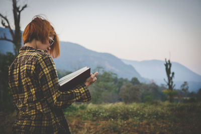 Rear view of woman standing on land against sky