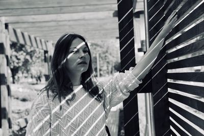 Portrait of young woman standing against building