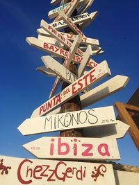 Low angle view of information sign against clear blue sky