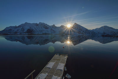 Scenic view of lake by snowcapped mountains against sky