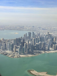 Aerial view of city by sea against sky