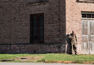 Portrait of senior adult man standing against old house