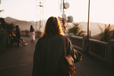 Rear view of people walking on street against sky