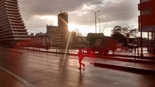 Man walking in city against cloudy sky