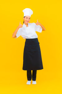 Portrait of a smiling woman standing against yellow background