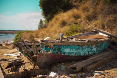 Abandoned boat moored on beach against sky