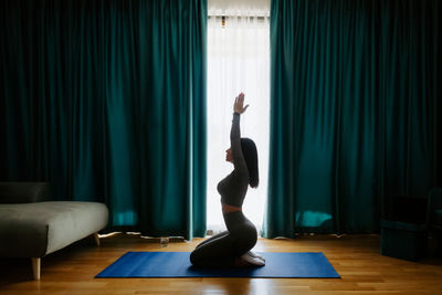 Full length of woman with arms raised on floor