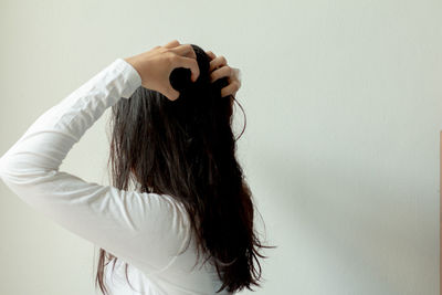 Rear view of woman standing against wall