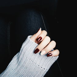 Close-up of woman hand with tattoo against black background