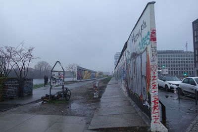 Vehicles on road against sky in city