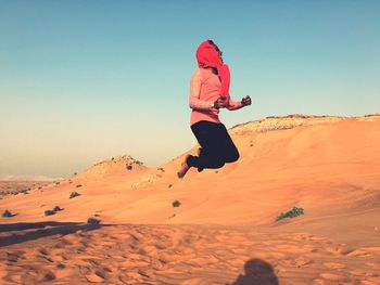 Man jumping in snow against clear sky