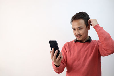 Mid adult man using smart phone against white background