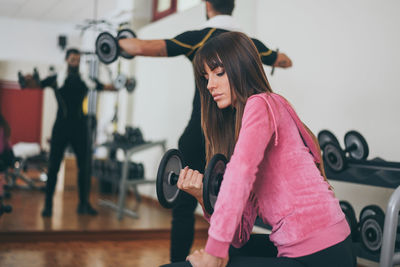 Determined young couple working out in gym. fit boy and girl doing exercise with weights 