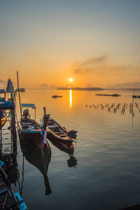 Fishing boats in sea at sunset