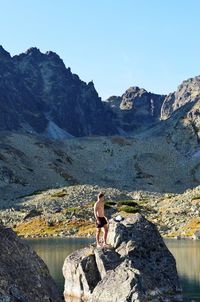 Man on rock by mountains against sky