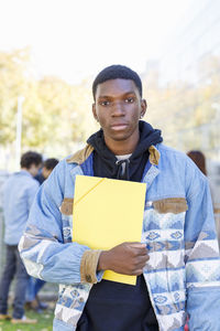 Teenager with yellow file on university campus