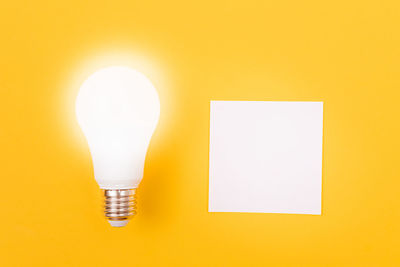 Close-up of light bulb against yellow wall