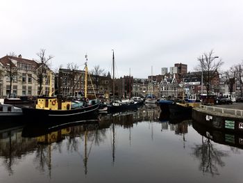 Boats moored at harbor against buildings in city