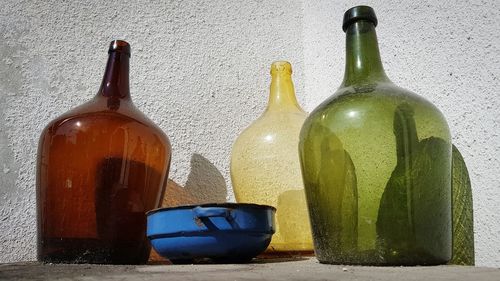 Close-up of bottles on table against wall