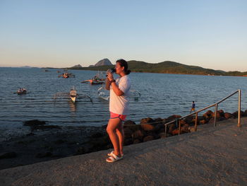 Full length of woman standing on beach against clear sky