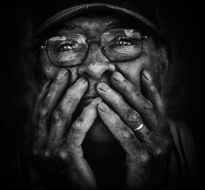 Close-up of senior man wearing eyeglasses against black background