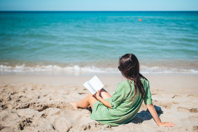 Side view of woman sitting at beach