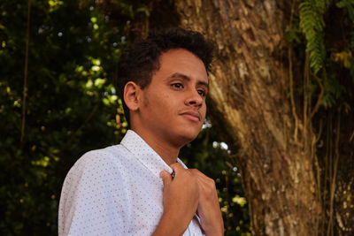 Low angle view of man holding collar against trees