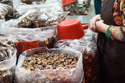 Midsection of female vendor with dried foods in sacks at market stall