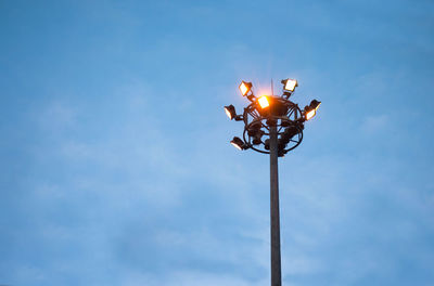 Low angle view of illuminated floodlight against blue sky