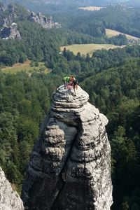 Rear view of people on rocky peak overlooking lush landscape