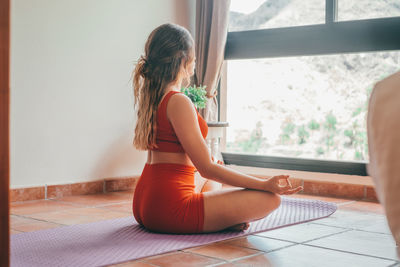 Rear view of woman sitting on floor at home