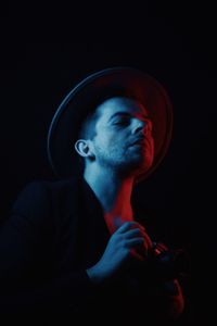 Portrait of young man smoking against black background